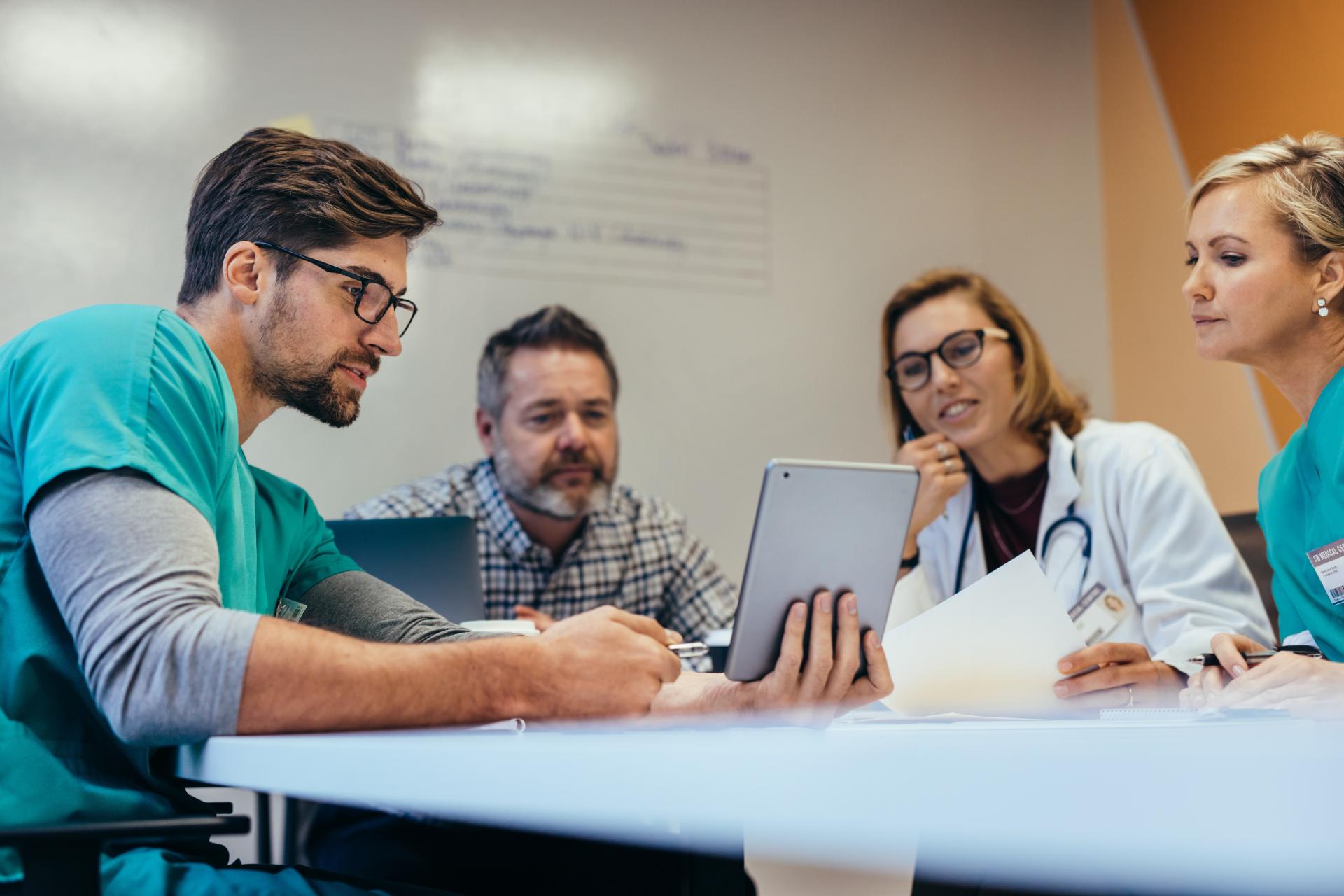 A group of doctors and nurses talking looking at a tablet