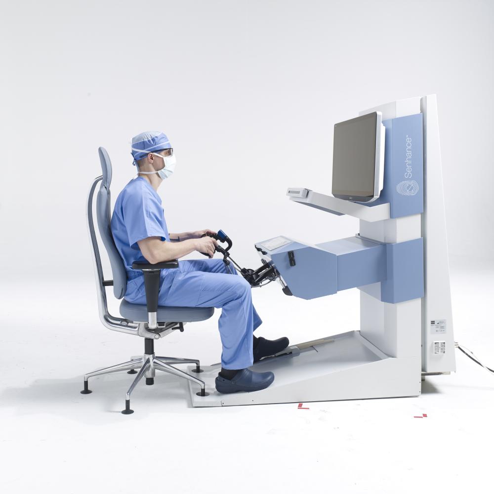 A doctor sitting at the controls of a Senhance System