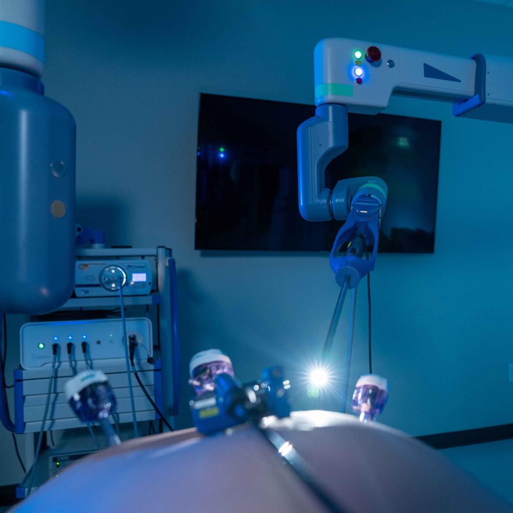 A Senhance robot with a light attached to it in a blue room